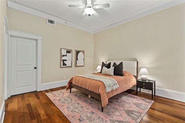 bedroom featuring visible vents, ornamental molding, wood finished floors, baseboards, and ceiling fan