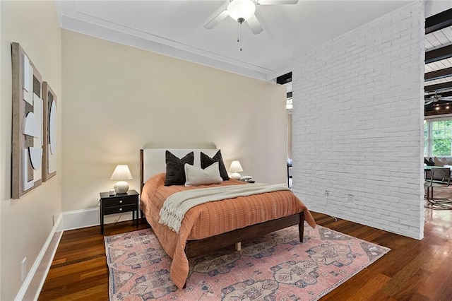 bedroom with a ceiling fan, baseboards, wood finished floors, and brick wall