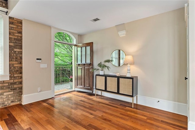 foyer entrance featuring baseboards, wood finished floors, and visible vents
