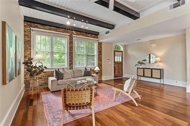 living area with baseboards, beam ceiling, wood finished floors, and visible vents