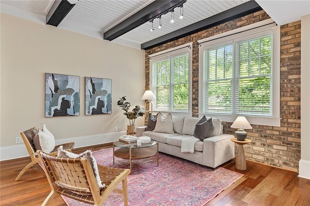 living room featuring brick wall, baseboards, and wood finished floors