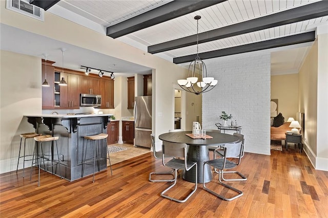 dining area featuring a notable chandelier, rail lighting, baseboards, light wood-type flooring, and visible vents