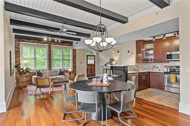 dining space with track lighting, light wood finished floors, a chandelier, baseboards, and beamed ceiling