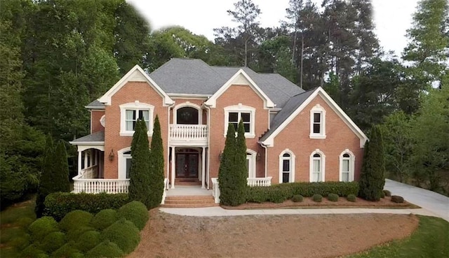 view of front of home with a balcony, covered porch, and brick siding