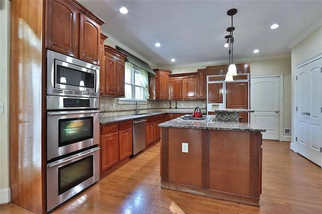 kitchen with built in appliances, tasteful backsplash, dark stone counters, and light wood finished floors