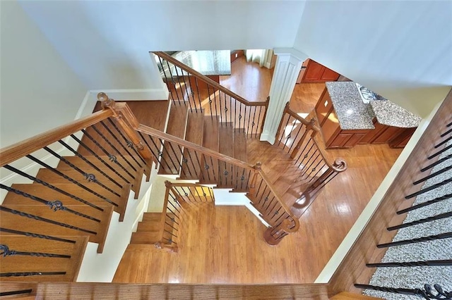 stairway with ornate columns and wood finished floors