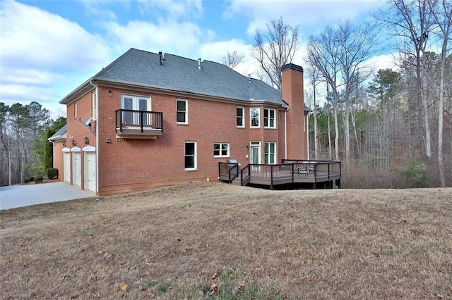 rear view of house featuring brick siding, a chimney, a balcony, a garage, and driveway