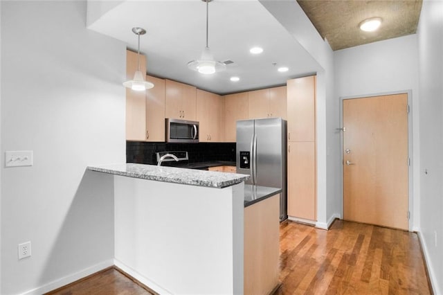 860 Peachtree St NE Unit 909, Atlanta, GA 30308 - kitchen with appliances with stainless steel finishes, light brown cabinetry, a peninsula, decorative backsplash, and light wood-style floors