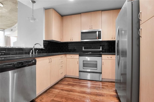 860 Peachtree St NE Unit 909, Atlanta, GA 30308 - kitchen with stainless steel appliances, light brown cabinetry, dark countertops, light wood-style floors, and tasteful backsplash