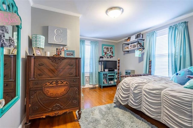 bedroom with ornamental molding and wood finished floors