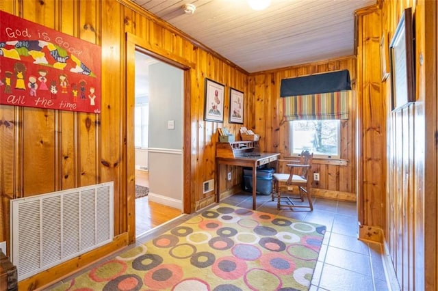 office space with baseboards, visible vents, and wooden walls