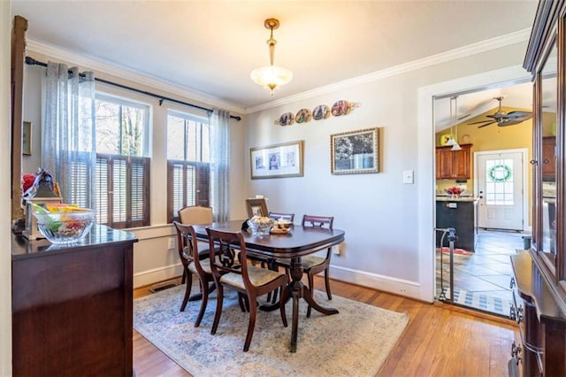 dining space featuring crown molding, lofted ceiling, a ceiling fan, wood finished floors, and baseboards