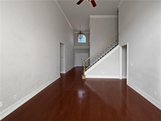 foyer entrance with ornamental molding, a towering ceiling, ceiling fan with notable chandelier, and dark hardwood / wood-style flooring