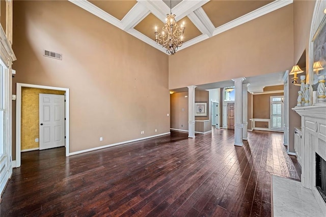 unfurnished living room featuring a chandelier, wood-type flooring, a tiled fireplace, beam ceiling, and decorative columns