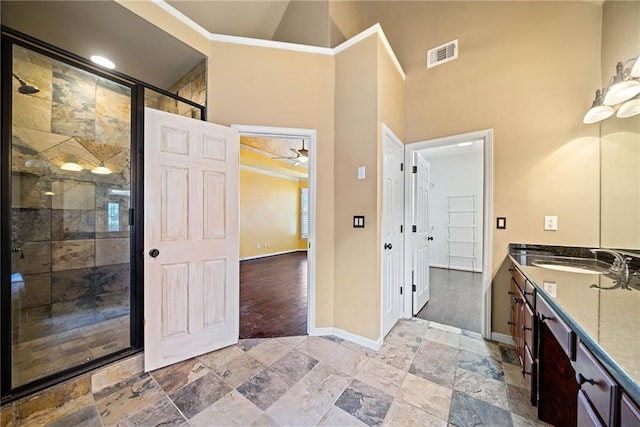 bathroom featuring ceiling fan, walk in shower, crown molding, and vanity