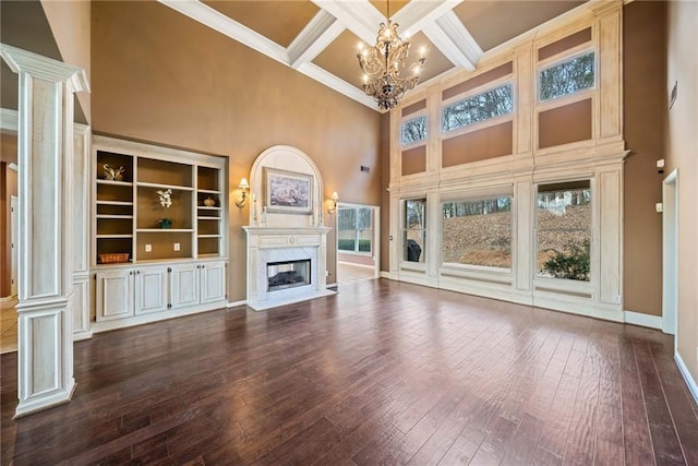 unfurnished living room with a fireplace, beamed ceiling, a towering ceiling, coffered ceiling, and a notable chandelier