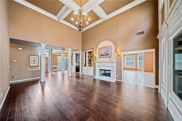 unfurnished living room featuring an inviting chandelier, beamed ceiling, ornate columns, a premium fireplace, and coffered ceiling