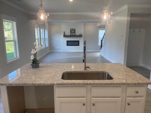 kitchen with pendant lighting, light stone countertops, white cabinetry, and sink