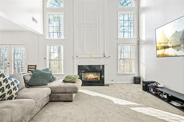 living room featuring carpet flooring, a high ceiling, french doors, and a fireplace