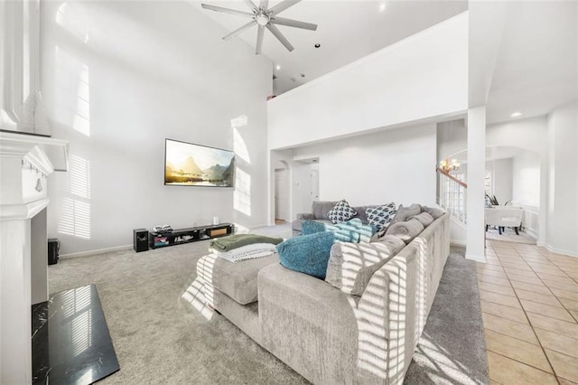 tiled living room with a high ceiling, ceiling fan with notable chandelier, and a wealth of natural light