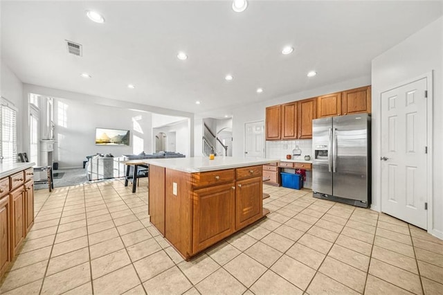 kitchen featuring tasteful backsplash, stainless steel fridge, a kitchen island, and light tile patterned flooring