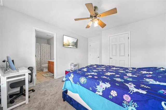 carpeted bedroom with ensuite bath and ceiling fan