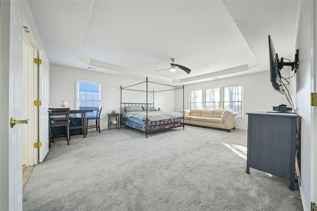 carpeted bedroom with a tray ceiling and ceiling fan