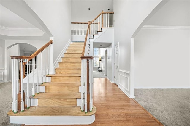 stairs with wood-type flooring and crown molding