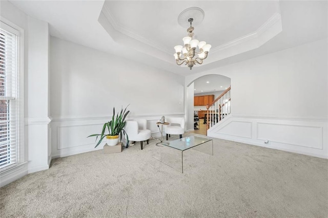 living area with a tray ceiling, carpet flooring, and a chandelier