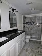 bathroom with toilet, marble finish floor, double vanity, and a stall shower