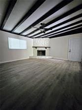 unfurnished living room with a fireplace, beam ceiling, and wood finished floors