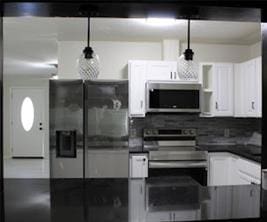 kitchen featuring dark countertops, white cabinetry, stainless steel appliances, and decorative backsplash