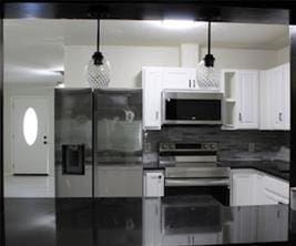 kitchen featuring appliances with stainless steel finishes, dark countertops, white cabinetry, and hanging light fixtures