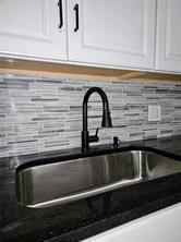 room details with decorative backsplash, a sink, white cabinets, and dark countertops