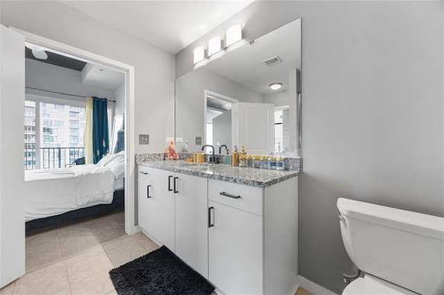 ensuite bathroom with visible vents, toilet, vanity, tile patterned floors, and ensuite bath