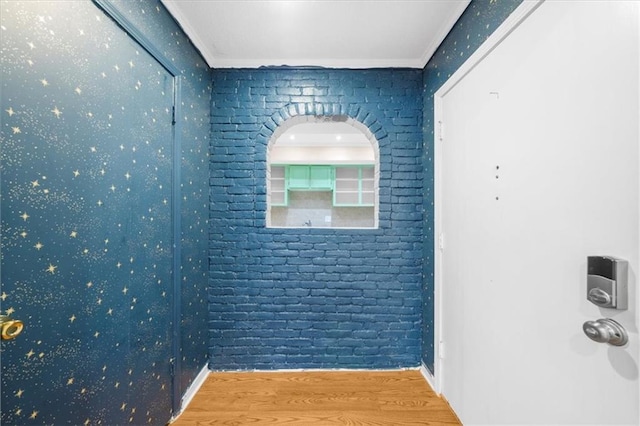 interior space with hardwood / wood-style flooring, crown molding, and brick wall