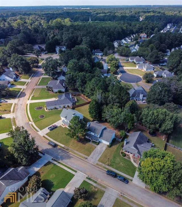 aerial view of property's location featuring nearby suburban area and a heavily wooded area