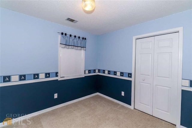 unfurnished room with carpet flooring, a textured ceiling, and baseboards