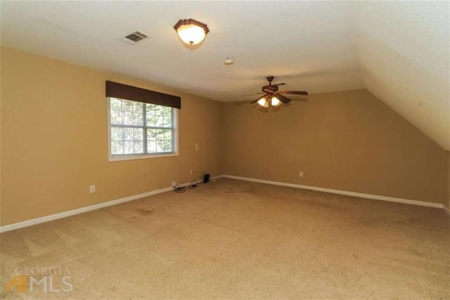 spare room with light carpet, a ceiling fan, baseboards, and vaulted ceiling
