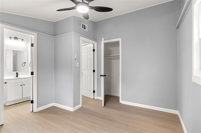 unfurnished bedroom featuring sink, light hardwood / wood-style floors, a closet, and ensuite bathroom