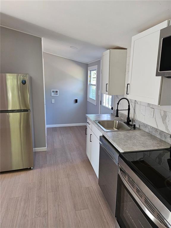 kitchen with stainless steel appliances, sink, white cabinets, and backsplash