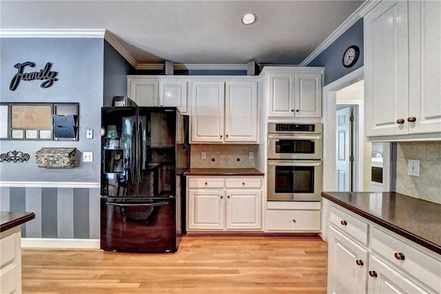 1595 Chadberry Way, Lawrenceville, GA 30043 - kitchen with black fridge, double oven, light wood finished floors, dark countertops, and crown molding