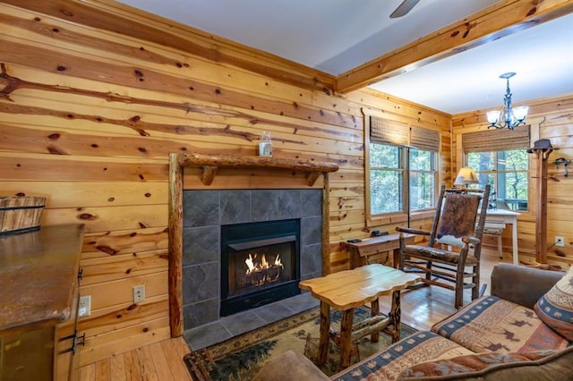 living room featuring a fireplace, wooden walls, light hardwood / wood-style flooring, and beamed ceiling