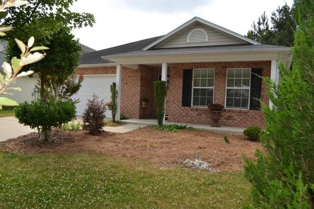 ranch-style home featuring covered porch, a garage, and a front lawn