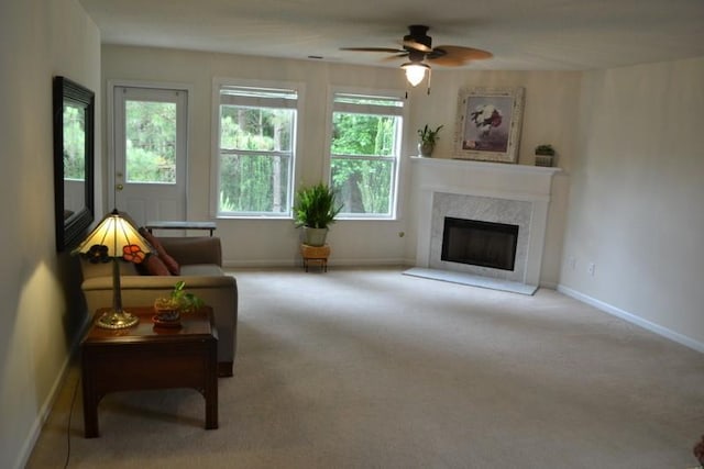 carpeted living room with a premium fireplace and ceiling fan