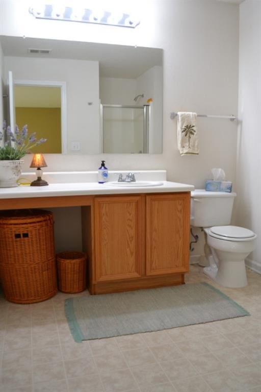 bathroom with vanity, toilet, and a shower with door