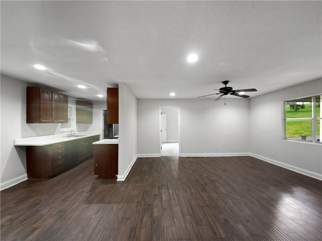 unfurnished living room with ceiling fan, sink, and dark hardwood / wood-style floors