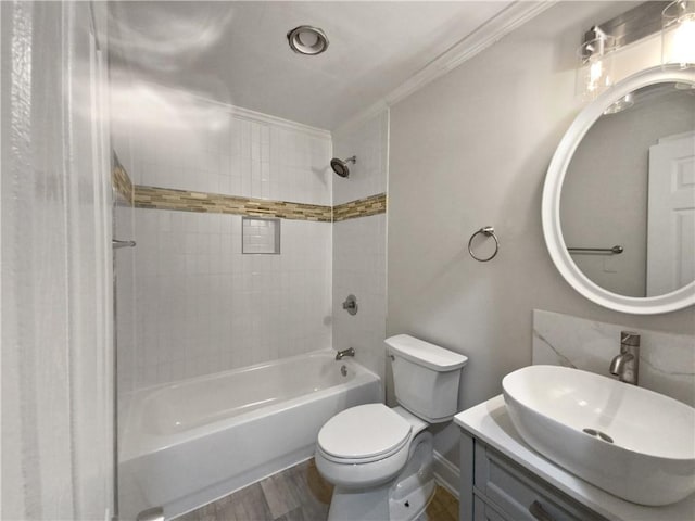 full bathroom featuring tiled shower / bath, hardwood / wood-style floors, ornamental molding, toilet, and vanity