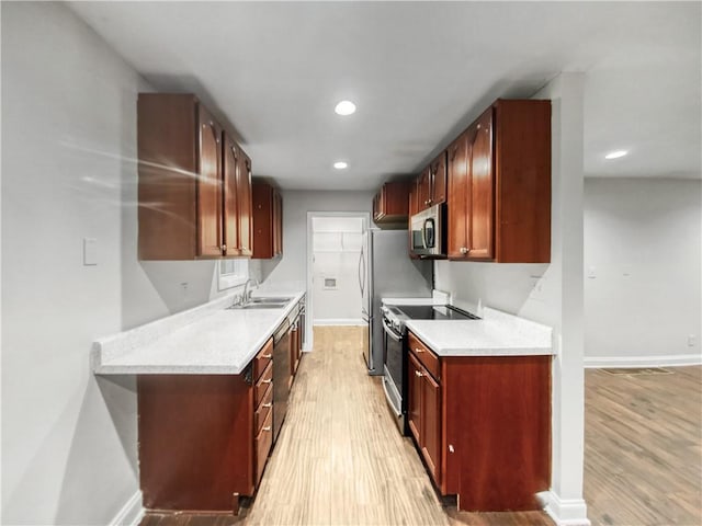 kitchen featuring sink, light hardwood / wood-style floors, light stone counters, and appliances with stainless steel finishes