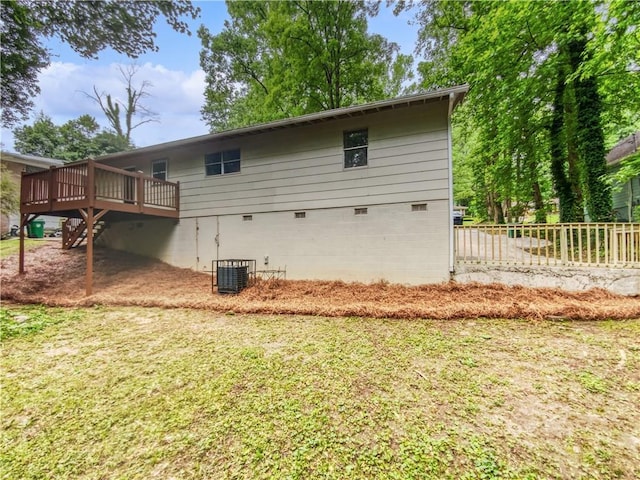 rear view of property with a deck, cooling unit, and a lawn